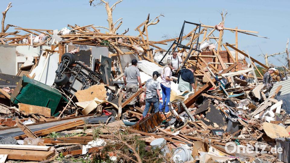 Eine Familie blickt nach einem Tornado durch die Trümmer ihres Hauses im Stadtteil Grayridge in Oklahoma. Bild: Alonzo Adams/AP/dpa