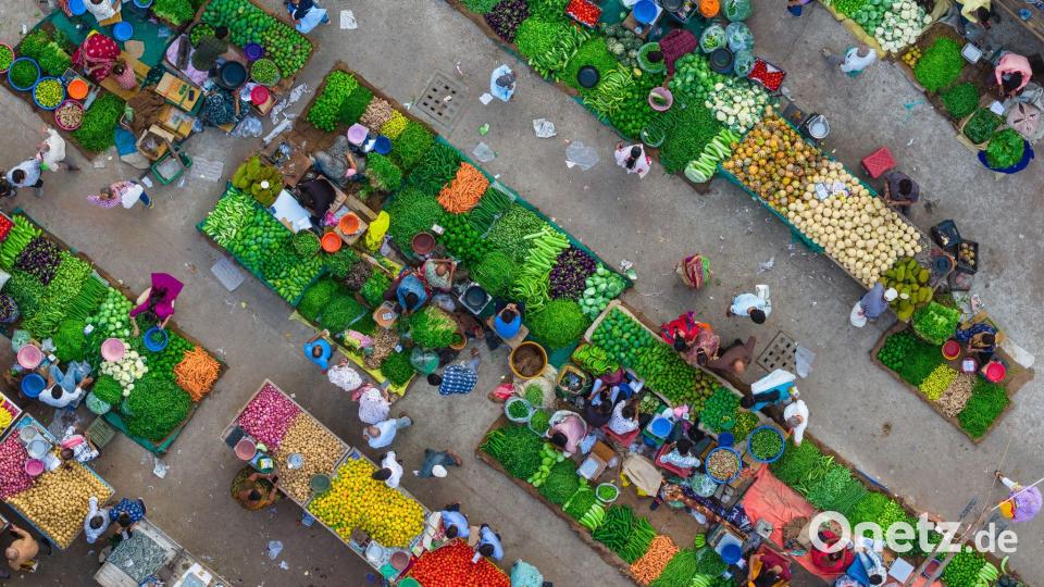 Eine Luftaufnahme zeigt das lebhafte Treiben auf einem Gemüsemarkt in Ahmedabad in Indien, wo Verkäufer frische Produkte anordnen und Kunden sich durch die engen Marktgassen bewegen. Bild: Saurabh Sirohiya/ZUMA Press Wire/dpa