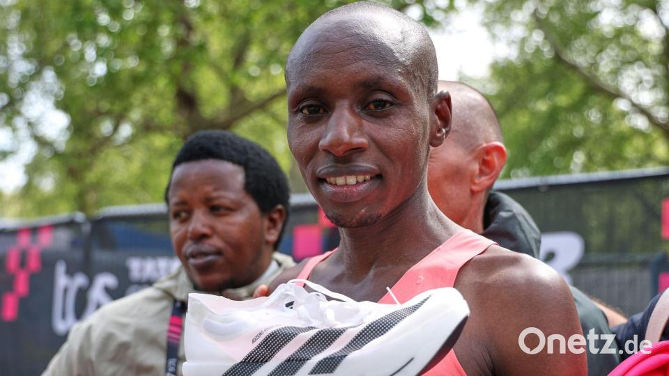 Posierte im Ziel mit einem Schuh: Sabastian Sawe. Bild: Ian Walton/AP/dpa
