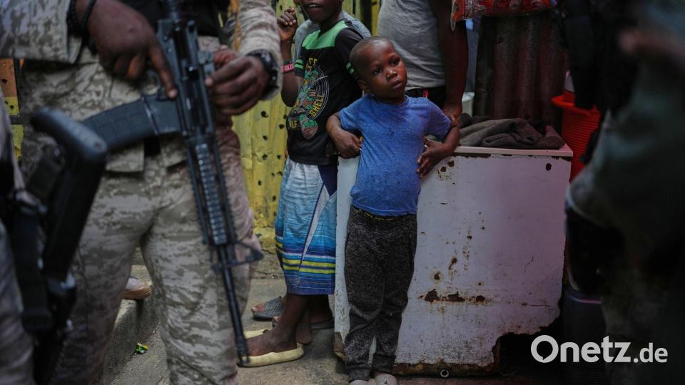 Kind neben bewaffnetem Polizisten in Unterkunft für Vertriebene in Port-au-Prince Bild: Odelyn Joseph/AP/dpa