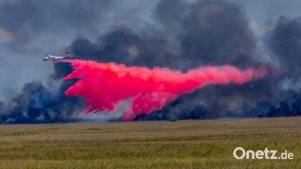 Ein Flugzeug wirft Feuerschutzmittel auf ein großes Waldfeuer. Bild: Pedro Portal/TNS via ZUMA Press Wire/dpa