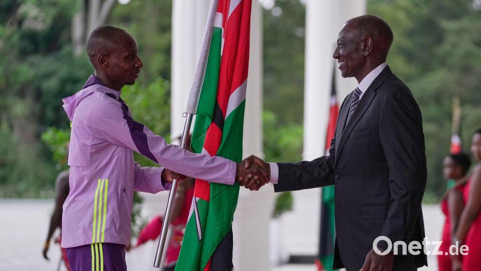 Der kenianische Marathon-Weltrekordler Sabastian Sawe (l) übergibt die kenianische Flagge an Präsident William Ruto. Bild: Brian Inganga/AP/dpa
