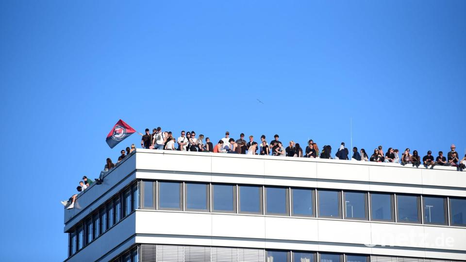 Teilnehmer stehen bei einer Demonstration mit dem Motto „Krieg und Krise haben System. Als Klasse vereint: Sozialismus erkämpfen!“ auf dem Dach eines Hauses in Hamburg. Bild: Daniel Bockwoldt/dpa