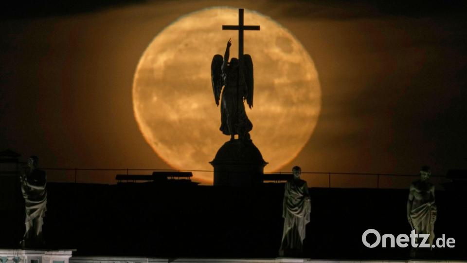 Der Mond geht hinter einer Engelsstatue auf der Alexandersäule auf dem Palastplatz über St. Petersburg auf. Bild: Dmitri Lovetsky/AP/dpa
