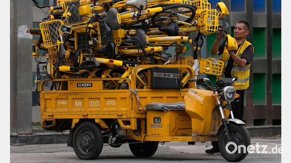 Hochstapler: Ein Arbeiter scannt Leihfahrräder auf seinem Transport-Dreirad in Peking. Bild: Andy Wong/AP/dpa