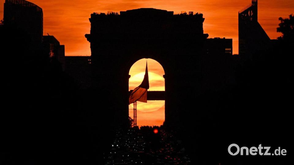 Die französische Nationalflagge weht unter dem Arc de Triomphe auf der Avenue des Champs Elysees während des sogenannten "Paris Henge"-Phänomens. Bild: Christophe Delattre/AFP/dpa