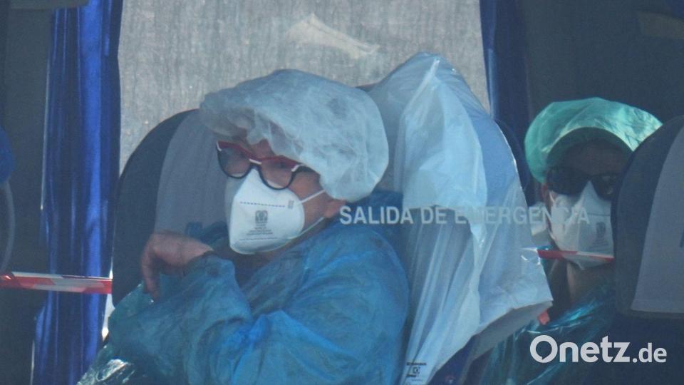 Die evakuierten Menschen trugen Schutzanzüge und Masken. Bild: Manu Fernandez/AP/dpa
