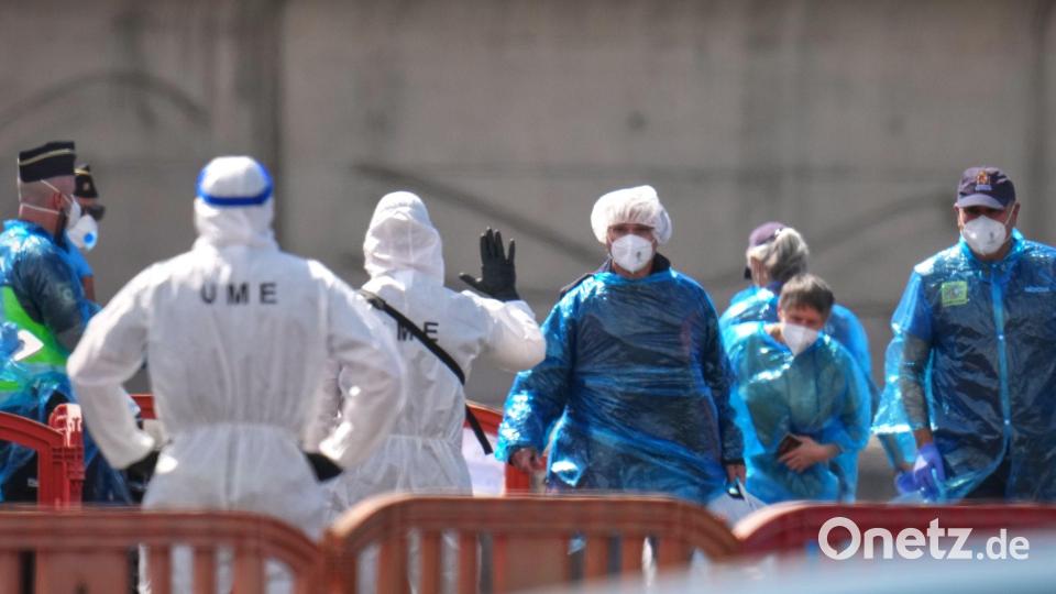 Person in Schutzbekleidung und mit Masken (r) gehen im Hafen von Granadilla auf Teneriffa an Land. Bild: Manu Fernandez/AP/dpa