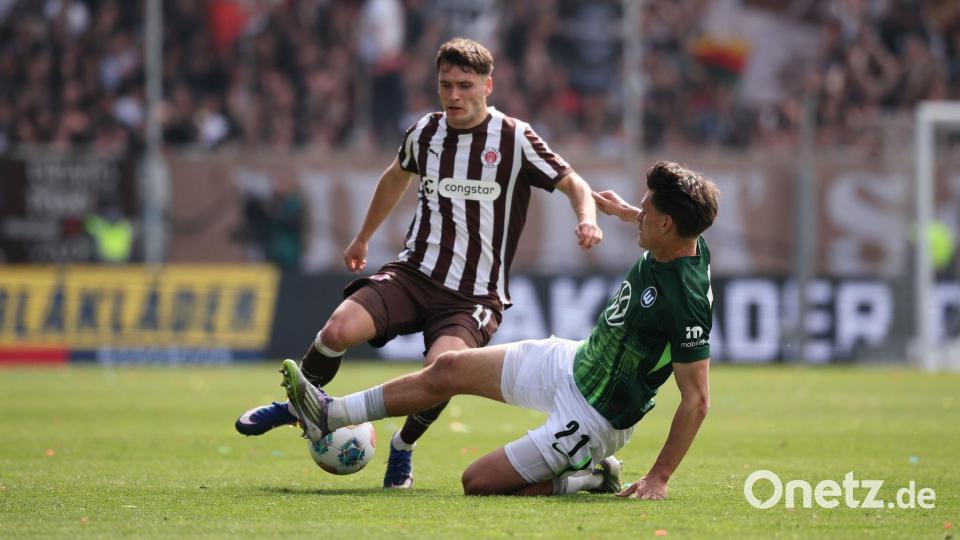 Abstiegskampf pur: Der Wolfsburger Joakim Maehle packt die Grätsche gegen St. Paulis Arkadiusz Pyrka aus. Bild: Christian Charisius/dpa
