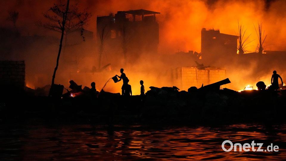 Anwohner versuchen mit Wassereimern ein Feuer zu bekämpfen, das in einer Armensiedlung in Manila ausgebrochen ist. Bild: Aaron Favila/AP/dpa