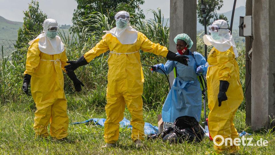 Mitarbeiter des Roten Kreuzes in Schutzkleidung desinfizieren sich. Bild: Moses Sawasawa/AP/dpa