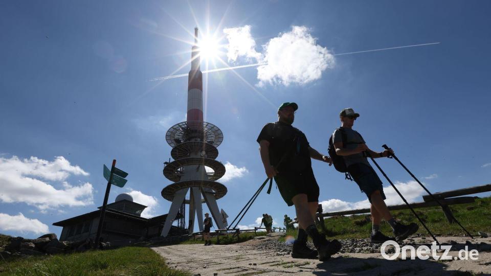 Wanderer gehen bei strahlendem Sonnenschein über einen Weg auf dem Brocken, im Hintergrund steht der Fernmeldeturm. Bild: Matthias Bein/dpa