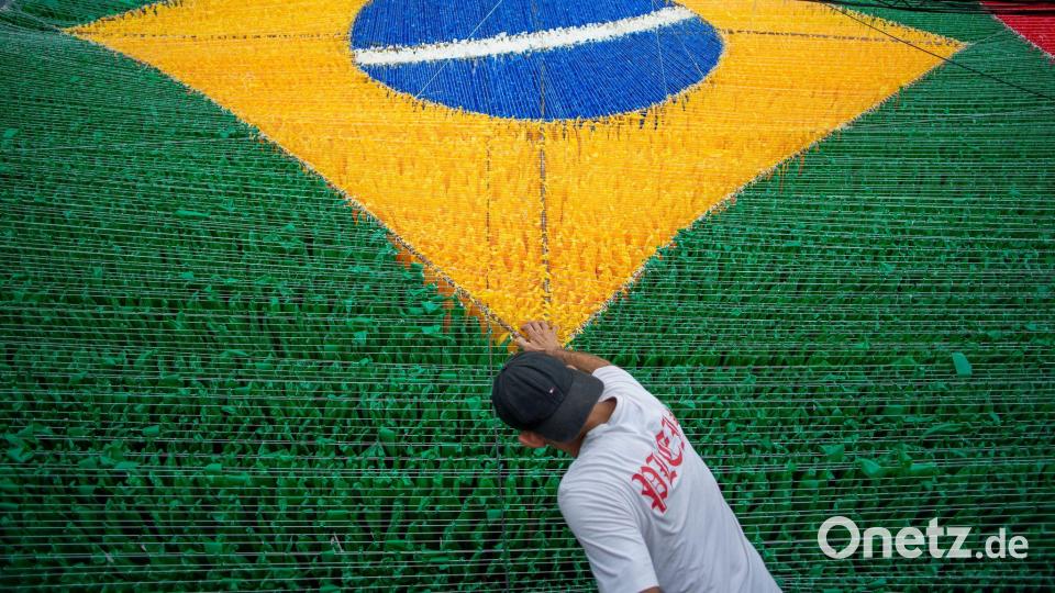 Eine Person gibt der hängenden Dekoration zur Feier der Fußballweltmeisterschaft 2026 auf der Rua 03 im Viertel Alvorada in Manaus, der Hauptstadt des brasilianischen Bundesstaates Amazonas, den letzten Schliff. Bild: Suamy Beydoun/dpa