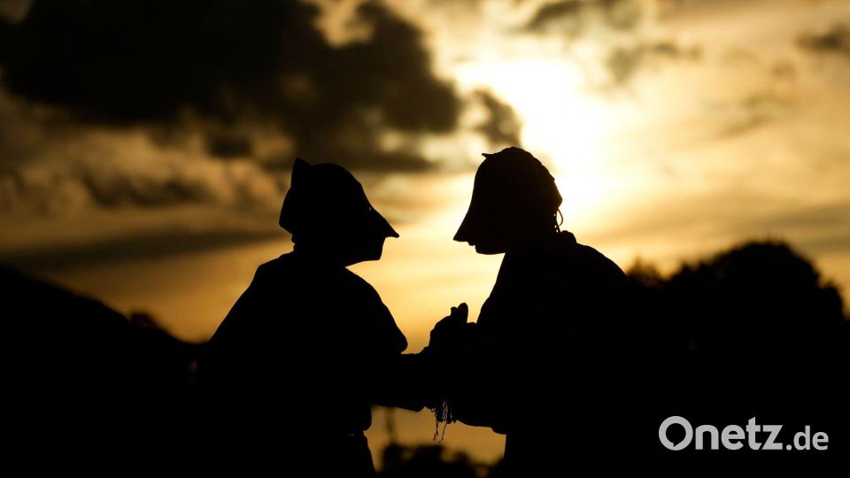 Maskierte Freischärler schauen sich bei Sonnenuntergang eine traditionelle Reitershow an. Bild: Eraldo Peres/AP/dpa