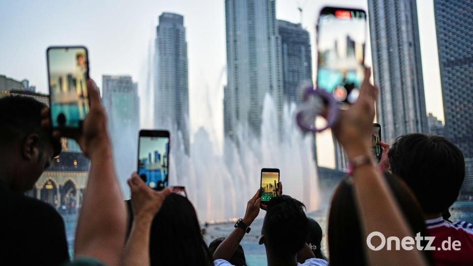 Eid al-Adha in Dubai: Besucher fotografieren den Brunnen vor der Skyline Bild: Fatima Shbair/AP/dpa