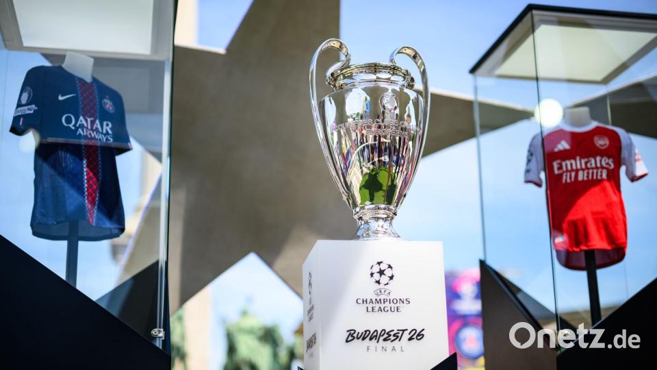 Der Pokal der Champions League steht zwischen den Trikots der Finalteams Paris Saint-Germain und FC Arsenal. Bild: Tom Weller/dpa