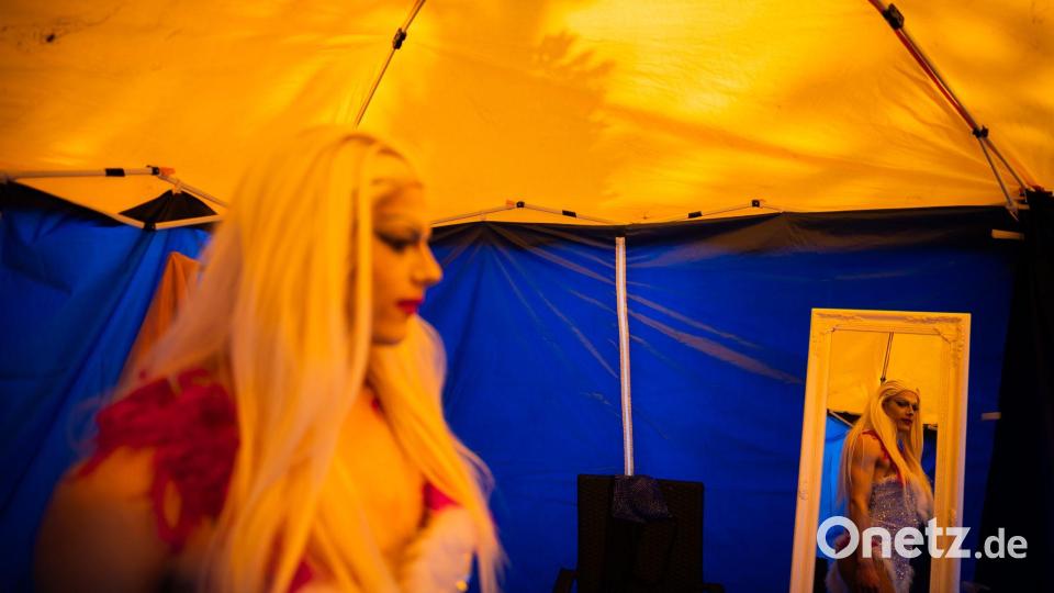 Dragqueen Janoma Bange steht beim Demokratiefest in Bad Freienwalde in einem Zelt und ist in einem Spiegel zu sehen. Bild: Christoph Soeder/dpa