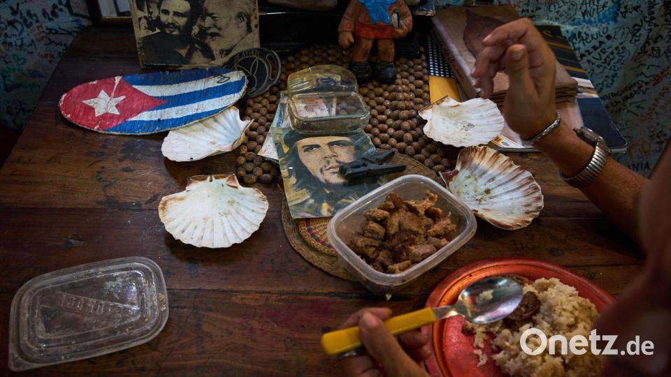 Eine Angestellte eines Souvenirgeschäfts in Havanna isst neben Bildern von Che Guevara, Fidel Castro und Ernest Hemingway. Bild: Ramon Espinosa/AP/dpa