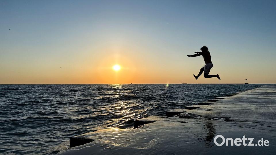 Ein junger Mann springt am frühen Morgen in Chicago von der Promenade am „Oak Street Beach“ in den Lake Michigan. Bild: Christian Charisius/dpa