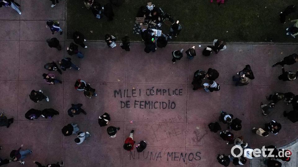 Demonstranten gehen in Buenos Aires in der Nähe eines Schriftzugs "Milei femicide accomplice" (Milei Frauenmord Mittäter), der sich auf Präsident Javier Milei bezieht, während eines Marsches zum Jahrestag der Frauenbewegung "Ni Una Menos" (Nicht eine weniger). Bild: Natacha Pisarenko/AP/dpa