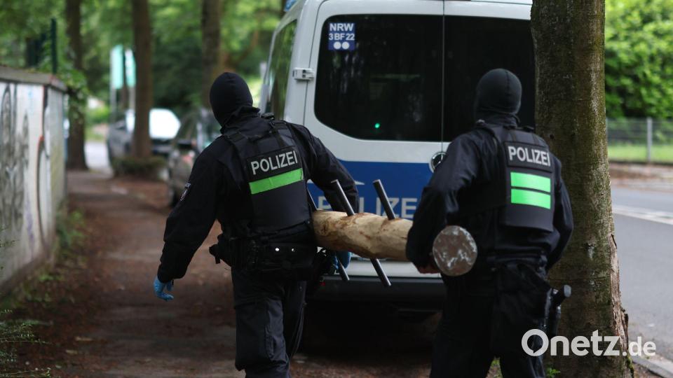Polizisten tragen einen Rammbock. Bild: Christoph Reichwein/dpa