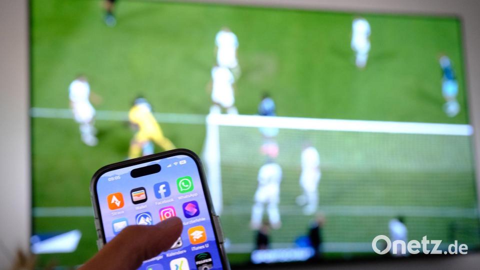 Nebenbei mal daddeln: Während das Fußballspiel läuft, schauen viele Zuschauer nebenbei aufs Handy. Symbolbild: Bernd Weißbrod/dpa