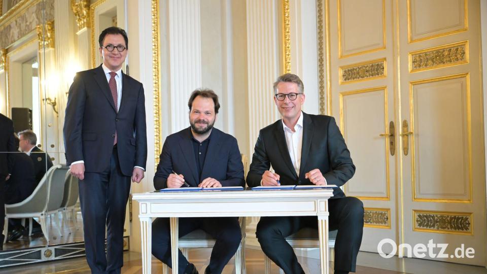 Im Königssaal des Nationaltheaters hat Popelka (m.) nun mit Bayerns Kunstminister Markus Blume (r.) den Vertrag unterschrieben, zur Freude von Staatsintendant Serge Dorny (l.) Bild: Malin Wunderlich/dpa