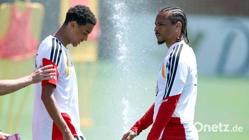 Jamal Musiala und Leroy Sané freuen sich über den Wassersprenger. Bild: Christian Charisius/dpa