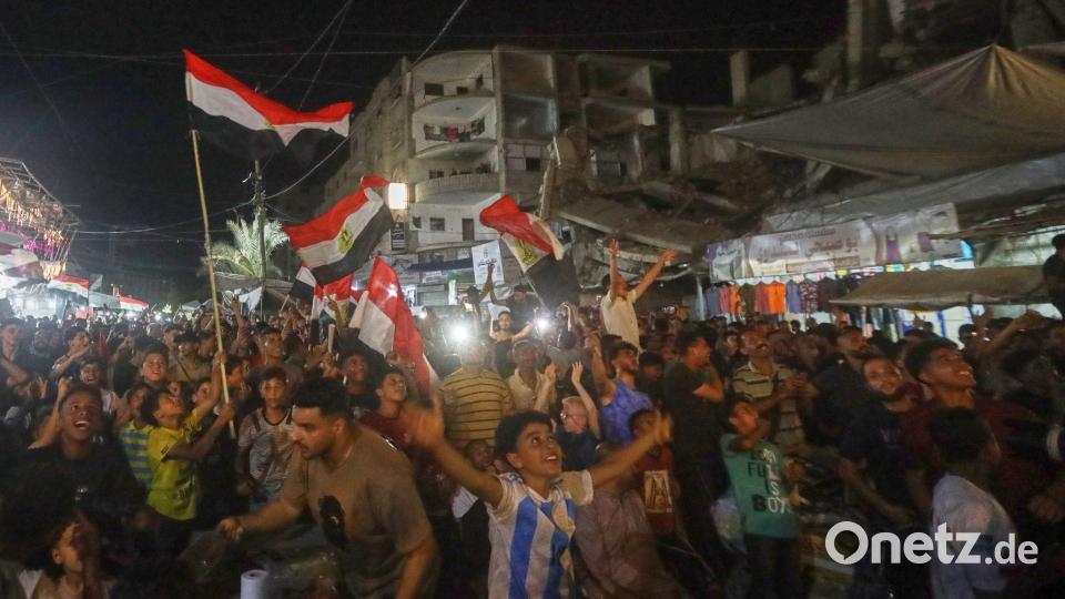 Menschen schwenke agyptische Flaggen und verfolgen im zentralen Gazastreifen das WM-Spiel Ägypten gegen Belgien auf einer Großbildleinwand. Bild: Yousef Al Zanoun/AP/dpa