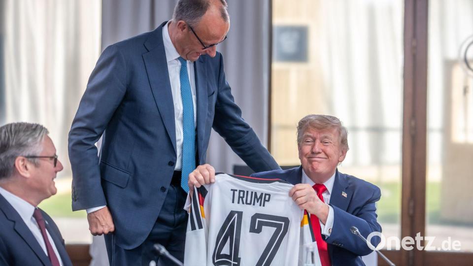 Merz überreicht Trump das Trikot mit der Nummer 47. Bild: Michael Kappeler/dpa-Pool/dpa