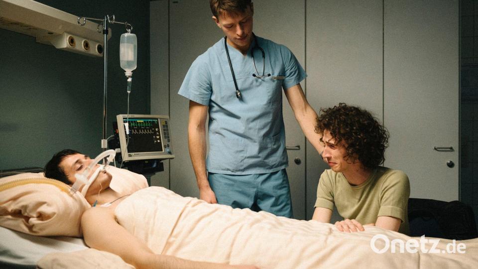 Bernhard Hoestermann (Clemens Bobke, Mitte) pflegt Heiko (Evangelos Tsarkowistas, links) während Dirk (Benjamin Viziotis, rechts) an seinem Bett sitzt - nachgespielte Szene aus dem zweiten Teil der ZDF-Dokuserie „AIDS - In Zeiten der Liebe“. Bild: Elliott Kreyenberg/ZDF/dpa