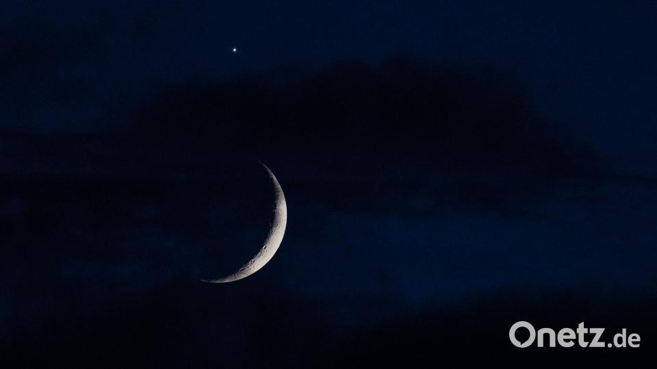 Der sichelförmige Mond wird am Abend hinter Wolken über Köln von der Venus (oben) begleitet. Bild: Rolf Vennenbernd/dpa