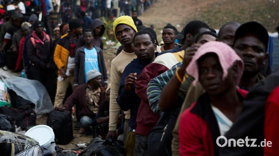 Vertriebene Migranten stehen in Durban in Südafrika vor einer Abschiebeeinrichtung Schlange. Bild: Uncredited/AP/dpa