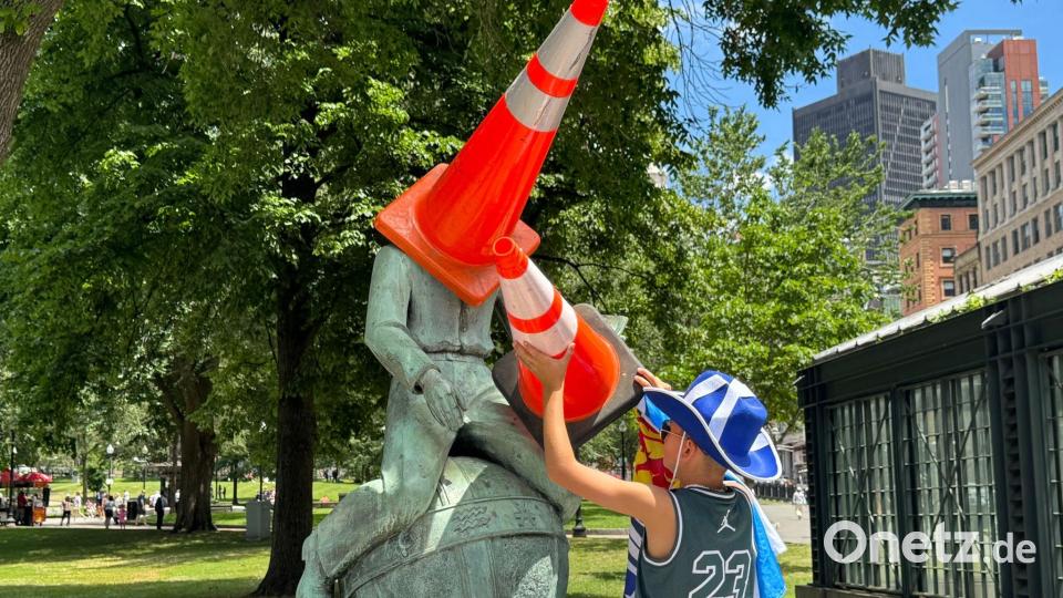 Ein schottischer Fußball-Fan setzt einer Statue in der Stadt Verkehrskegel auf. Bild: Jordan Raza/dpa
