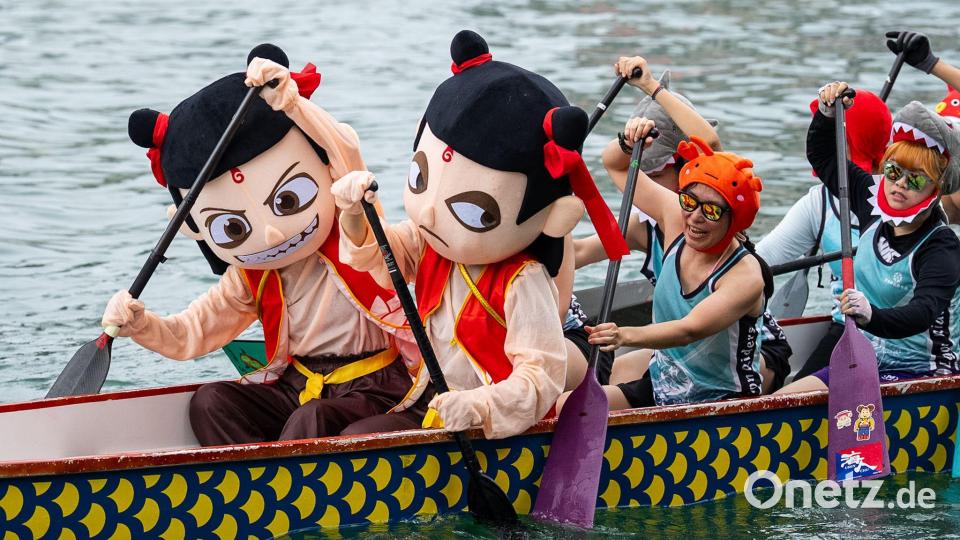 Teilnehmer in bunten Kostümen rudern beim Drachenbootfest in Hongkong. Bild: Chan Long Hei/AP/dpa