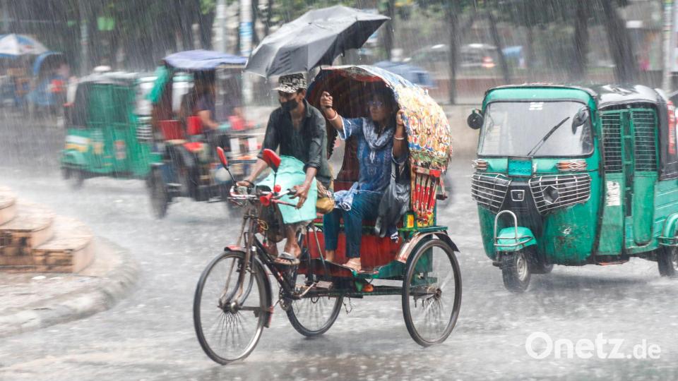 Menschen fahren im Monsunregen durch eine belebte Straße in Dhaka in Bangladesch. Bild: Md. Rakibul Hasan Rafiu/ZUMA Press Wire/dpa