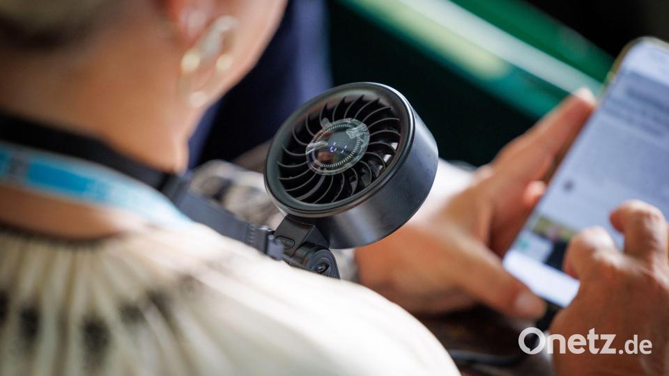 Extreme Hitze: Ein kleiner Ventilator soll auf der Tribüne helfen. Bild: Friso Gentsch/dpa