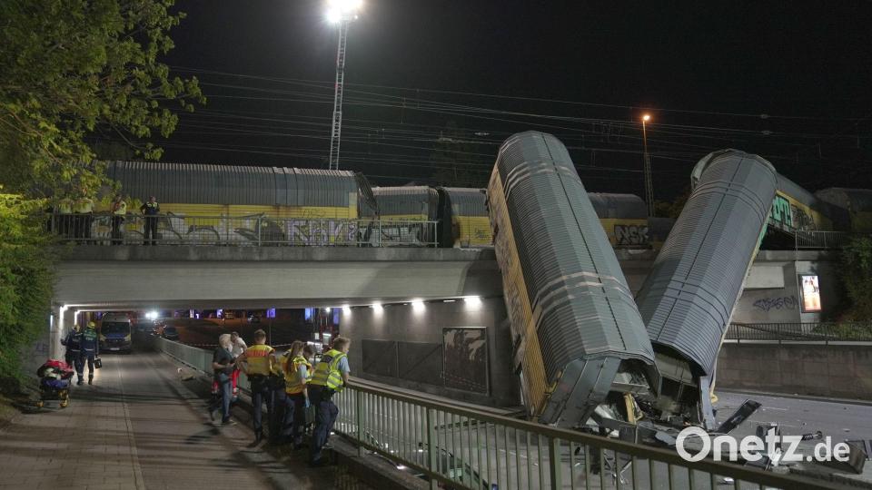 Zwei Waggons eines Güterzugs liegen auf einer Straße in München, nachdem sie von einer Brücke gestürzt sind. Bild: Ehsan Monajati/dpa