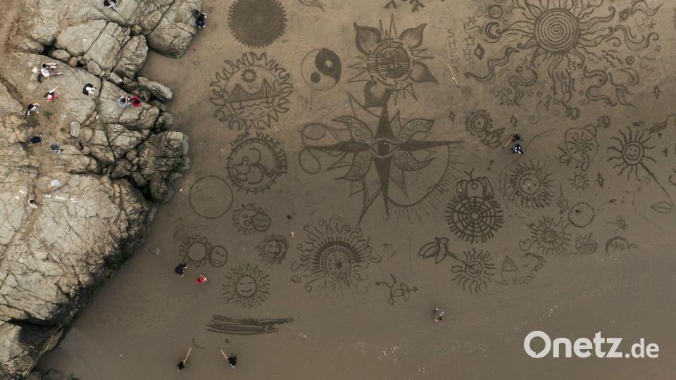 Menschen versammeln sich am Ocean Beach in San Francisco, um bei einer von Künstler Andres Amador organisierten Veranstaltung Kunstwerke im Sand zu gestalten. Bild: Stephen Lam/San Francisco Chronicle/AP/dpa