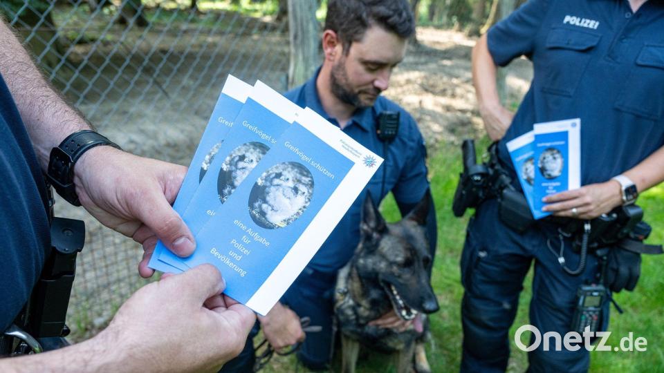 Polizeibeamte informieren Spaziergänger in einem Wald mit Infomaterial über Maßnahmen gegen Straftaten an Wildtieren. Bild: Armin Weigel/dpa
