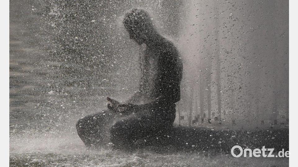 Eine Person erfrischt sich während der Hitzewelle in Paris in einem Brunnen in der Nähe des Eiffelturms. Bild: Christophe Ena/AP/dpa