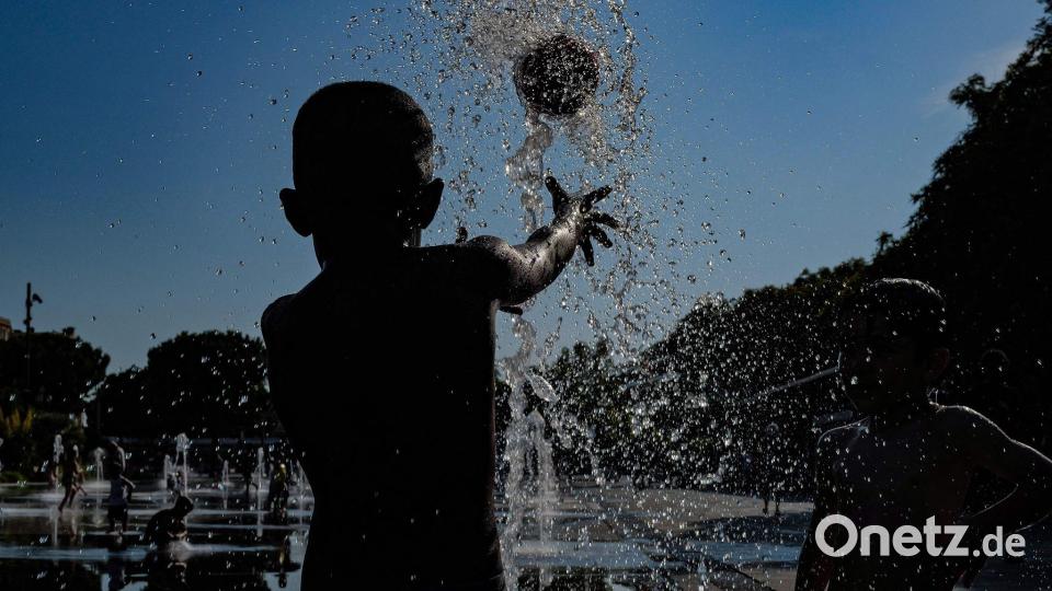 Kinder spielen mit einem Ball in einem Springbrunnen in Nizza. Bild: Valery Hache/AFP/dpa