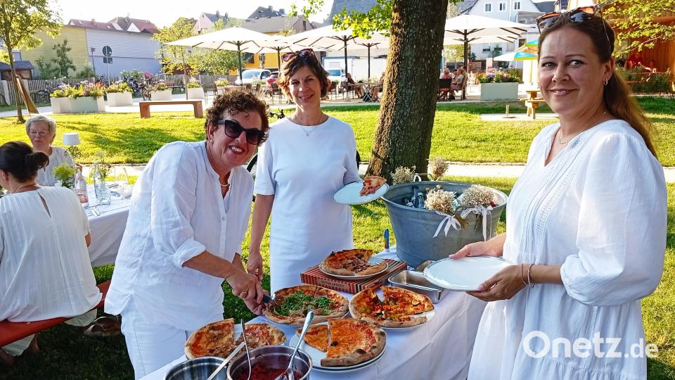 Christa Kastner versorgt die Tischnachbarn mit frischen Pizzaschnitten. Bild: Oswald Zintl
