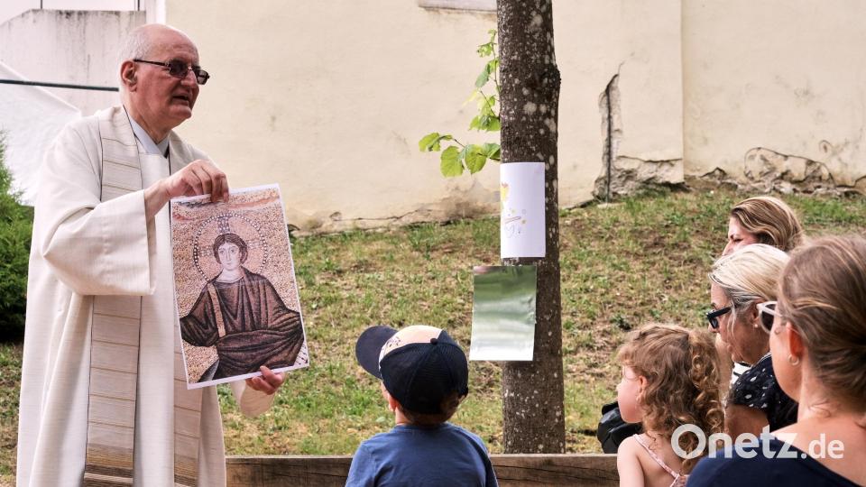 Auch Pfarrer Alois Berzl hatte ein Bild eines Superhelden dabei: Mit einem Bild von Jesus trat er an die jungen Besucherinnen und Besucher der Kinderandacht heran. Bild: Peter Ringeisen