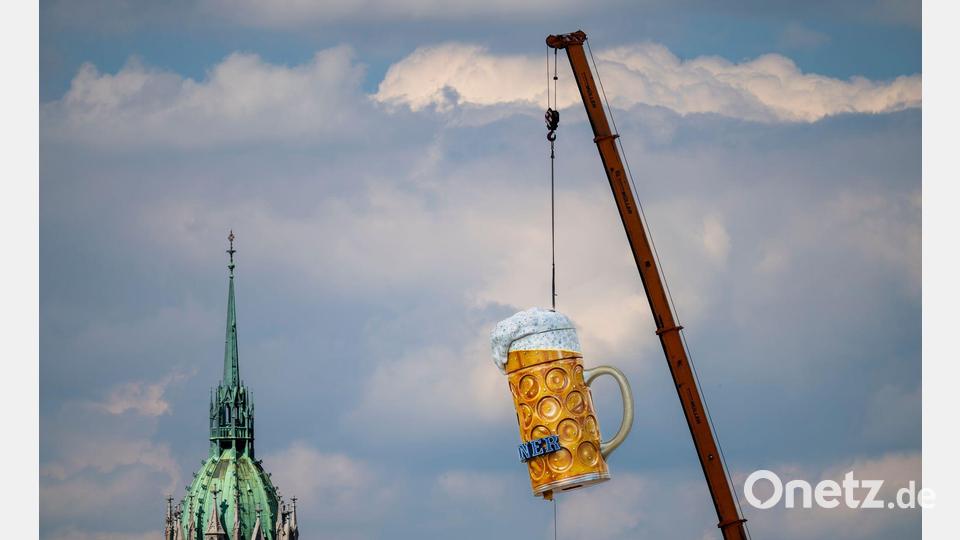 Ein übergroßer und rund 1,5 Tonnen schwerer Bierkrug wird mit einem Kran auf der Theresienwiese an seinen Platz gehoben. Das 191. Oktoberfest beginnt dieses Jahr am 19. September 2026 und endet am 04. Oktober 2026. Bild: Peter Kneffel/dpa