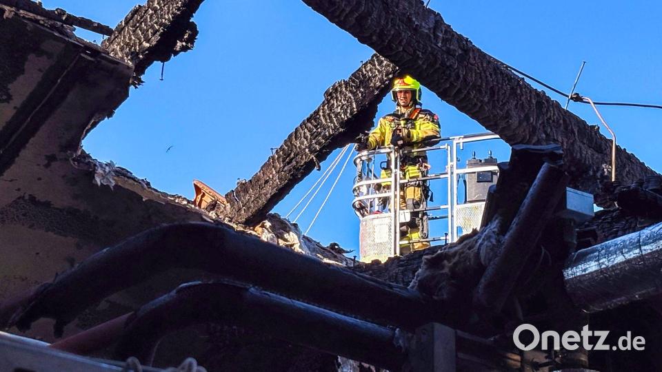 Ein Feuerwehrmann untersucht von einer Drehleiter aus den ausgebrannten Dachstuhl. (Handoutbild) Bild: Landkreis Ludwigslust-Parchim/dpa
