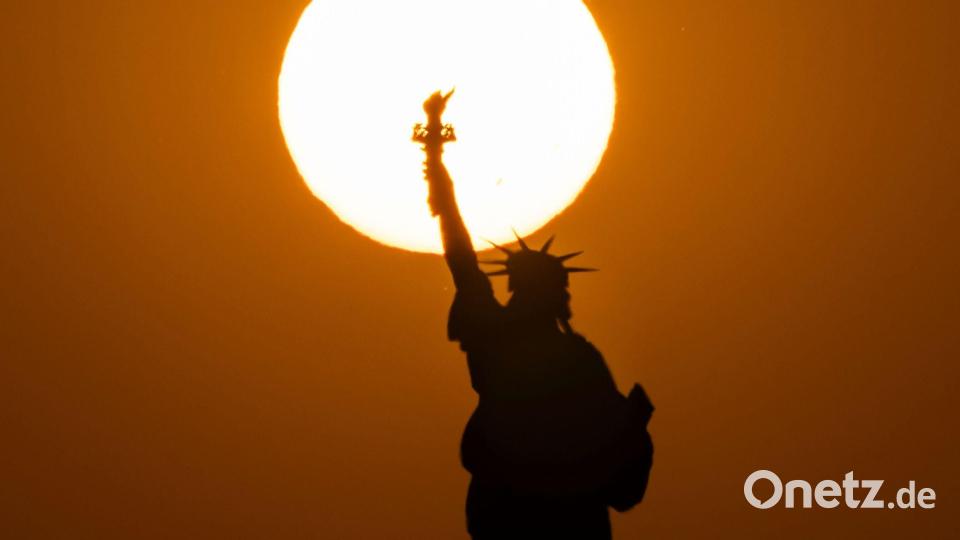 Die Freiheitsstatue in New York zeichnet sich vor der untergehenden Sonne ab. Bild: Yuki Iwamura/AP/dpa