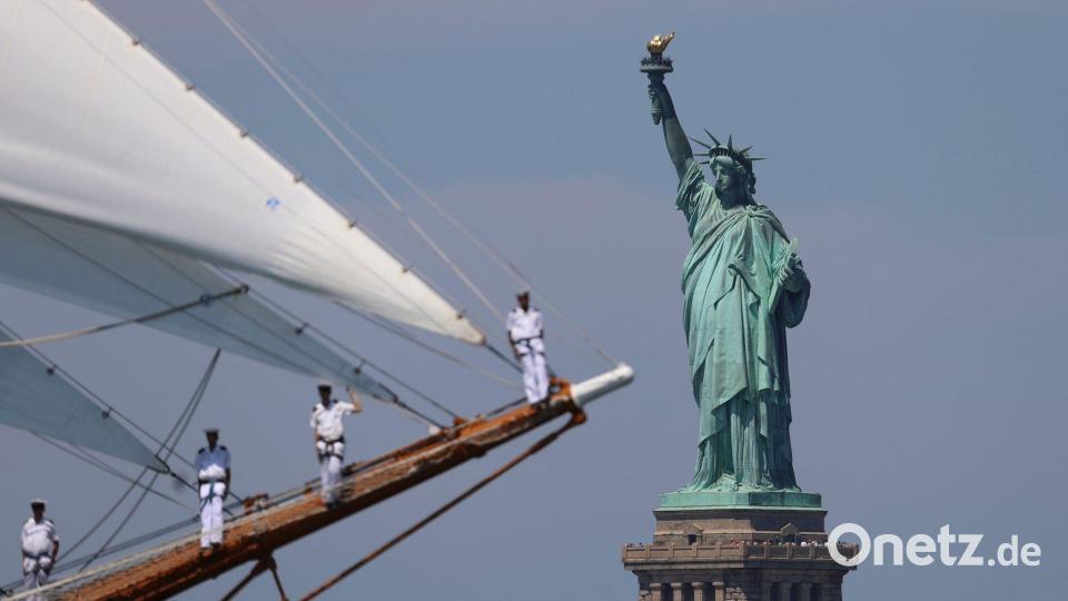 Die Freiheitsstatue ist zu sehen, während Seeleute eines Großseglers vorbeisegeln. Bild: Pamela Smith/AP/dpa