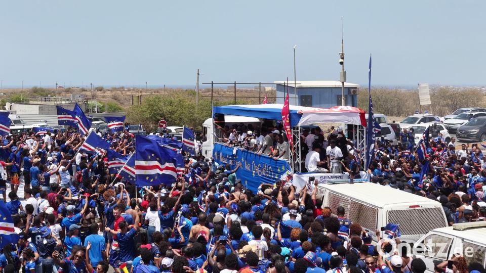 Fans laufen in Praia neben dem Bus der kapverdischen Fußballnationalmannschaft her. Bild: Uncredited/AP/dpa