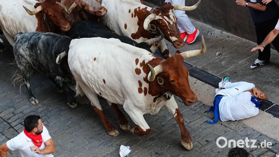 Feiernde laufen beim zweiten Stierlauf des San-Fermín-Festes neben den Kampfstieren. Bild: Miguel Oses/AP/dpa